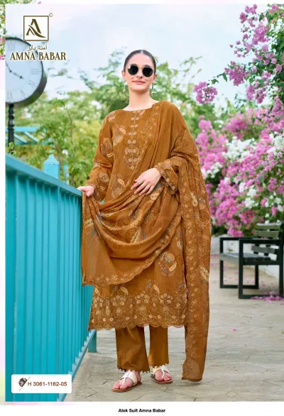 Alok Suit Amna Babar: Model wearing an ochre salwar suit with floral patterns and heavy thread work along the hem and neckline.