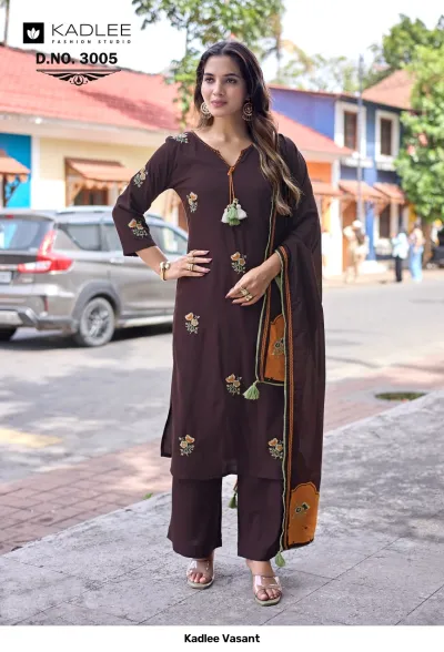 Kadlee Vasant Vol 3005, brown salwar suit with floral thread work, tassels, and matching dupatta, worn by a woman outdoors.