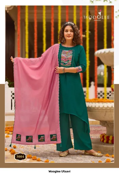 Wooglee Utsavi 3004: Teal green solid salwar suit with high-low kurti, embroidered chest patch, and light pink dupatta.