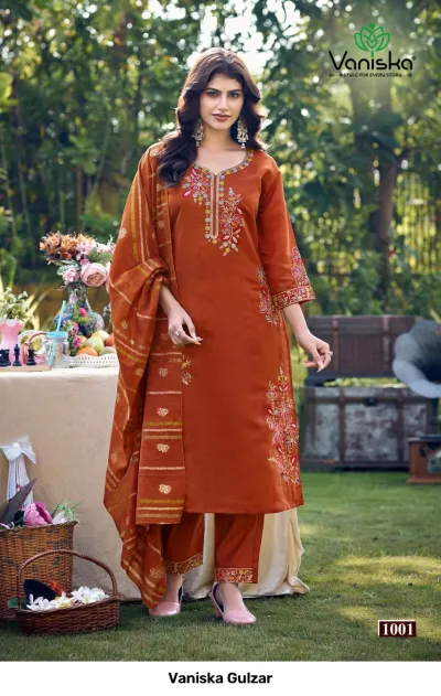 Vaniska Gulzar: Rust-orange salwar suit with detailed thread and zari embroidery, matching trousers, and a gold striped dupatta.