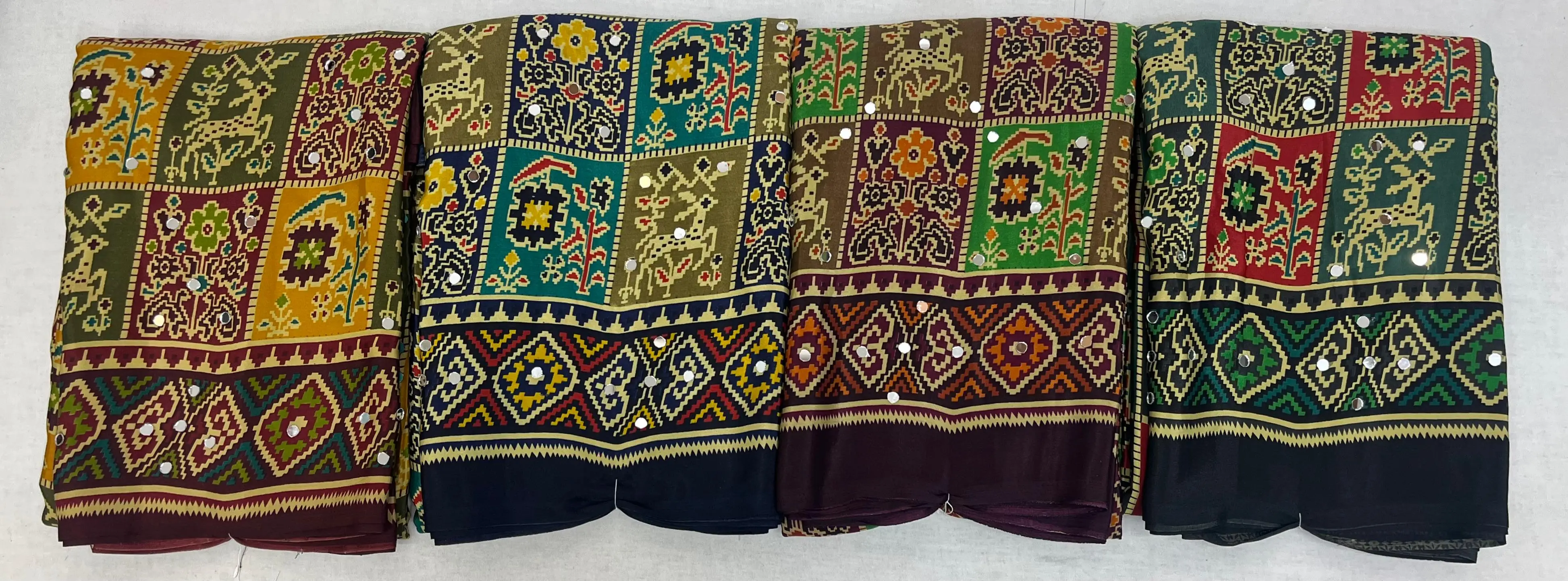 Wholesale Ajrak Print Mirror Work Sarees: Multi-colored printed sarees with geometric patterns and mirror work embellishments.