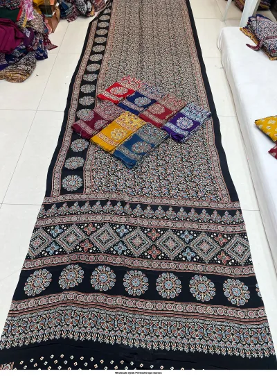 Wholesale Ajrak Printed Crepe Sarees: Catalog layout featuring a black saree with geometric circular patterns and multiple folded fabric displays.