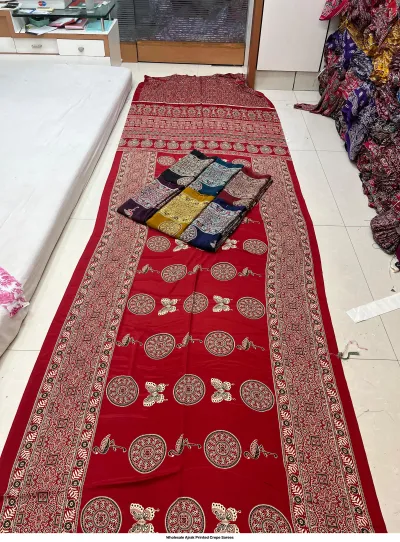 Wholesale Ajrak Printed Crepe Sarees: Catalog layout showing a red saree with butterfly and circular Ajrak prints alongside folded fabric options.