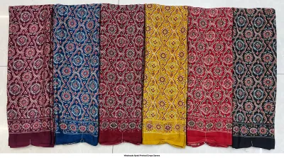 Wholesale Ajrak Printed Crepe Sarees: Six folded sarees in various colors with geometric and floral Ajrak prints.