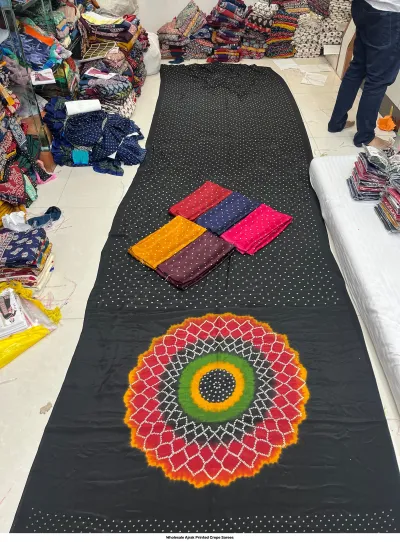 Wholesale Ajrak Printed Crepe Sarees: Catalog layout showing a black saree with geometric circular and butterfly prints and folded fabric swatches.