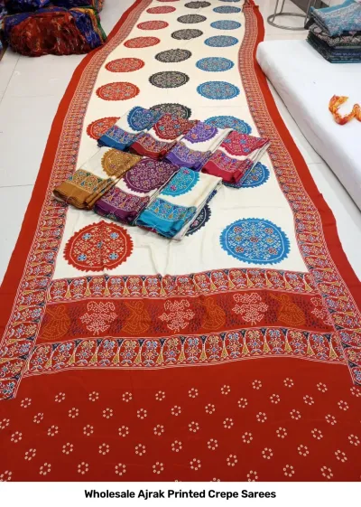 Wholesale Ajrak Printed Crepe Sarees: Six colorful folded sarees with uniform geometric floral Ajrak block prints.