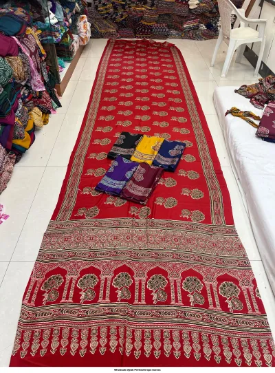 Wholesale Ajrak Printed Crepe Sarees: Seven colorful folded sarees with consistent floral Ajrak block print motifs.