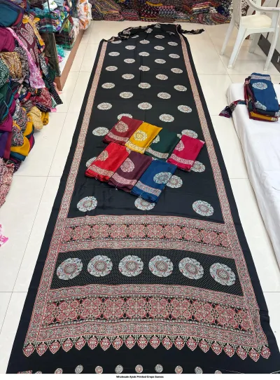 Wholesale Ajrak Printed Crepe Sarees: Six folded sarees featuring geometric and circular Ajrak print patterns in assorted colors.