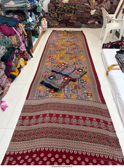 Wholesale Ajrak Printed Crepe Sarees: Seven folded sarees in multiple colors featuring repeating circular floral Ajrak prints.