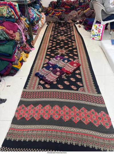 Wholesale Ajrak Printed Crepe Sarees: Seven folded sarees in various colors with consistent repeating floral Ajrak prints.