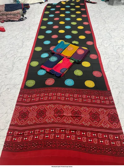 Wholesale Ajrak Printed Crepe Sarees: Six folded sarees with multicolored geometric and floral block print patterns.