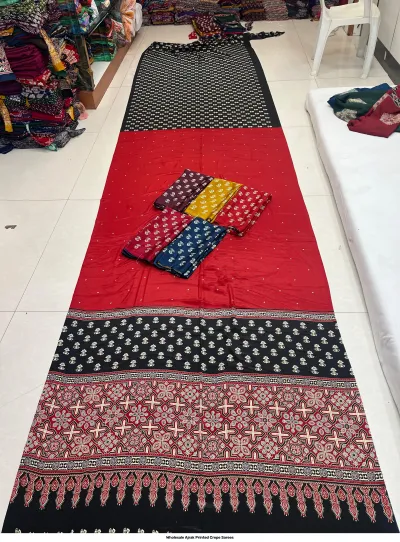 Wholesale Ajrak Printed Crepe Sarees: Catalog layout featuring a black saree with intricate floral and circular Ajrak patterns and fabric swatches.
