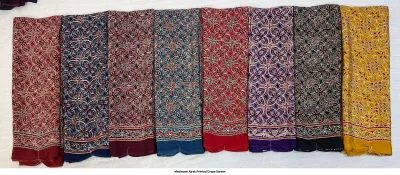 Wholesale Ajrak Printed Crepe Sarees: Seven folded sarees in multiple colors with intricate leaf Ajrak block print patterns.